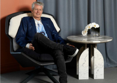 Neil Cownie seated next to the White Caps Coffee Table he designed